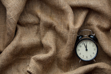 Vintage alarm clock on jute background