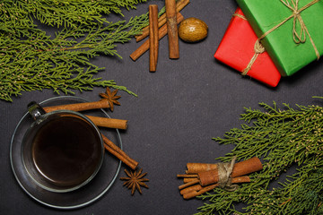 Christmas composition. Christmas gifts, snowflakes, a cup of coffee, cinnamon sticks, anise sprouts, spruce branches on a black background. top view, space for copying text.