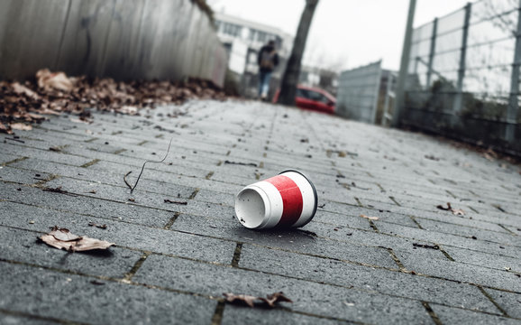 Weggeworfener leerer Kaffeebecher liegt auf Gehweg. 