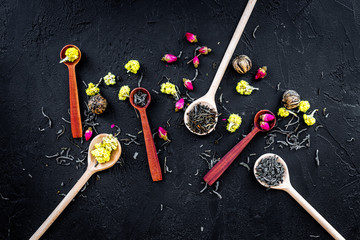 Fototapeta na wymiar Aromatic tea. Wooden spoons with dried tea leaves, flowers and spices on black background top view