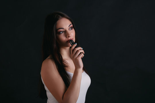 Young woman vaping e-cigarette on black