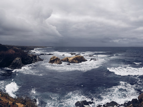Rocks in the blue ocean with cloudy windy moody weather