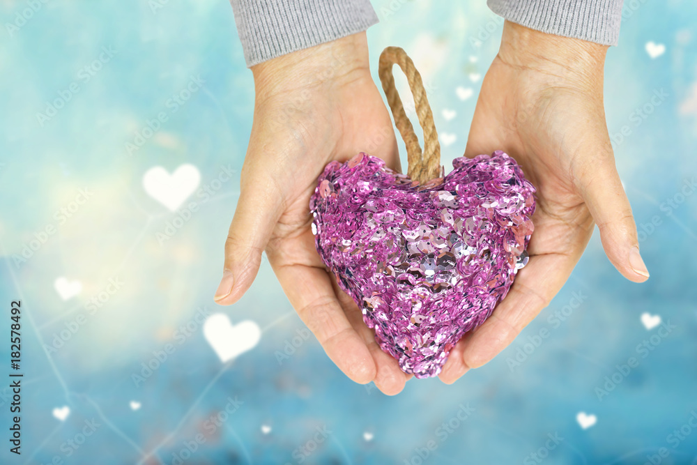 Wall mural hands holding pink heart on blue lovely background