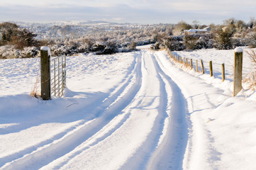 Fototapeta na wymiar Snow covered rural lane with tyre tracks