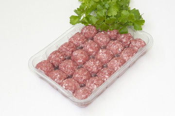 albondigas de carne en un envase de plastico y perejil fresco, sobre un fondo blanco