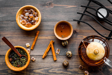 Tea ceremony concept. Tea pot, cups, dry tea leaves, sugar on dark wooden background top view