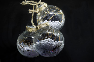 Handmade transparent Christmas balls filled with white balls and dry twigs on a black background. Happy New Year and Merry Christmas greeting card 2018.