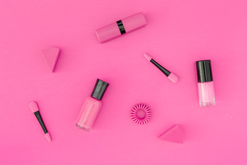 Bright decorative cosmetics. Pink nail polish and lipstick on pink background top view copyspace