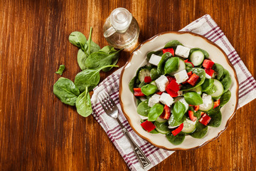 Fresh spinach salad with feta, cucumber and red paprika on a pla