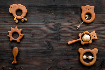 Cute wooden handmade toys for newborn on dark wooden background top view copyspace