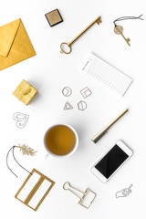 Office desk in trendy gold color. Glittering stationery near cup of tea, cell phone   on white background top view