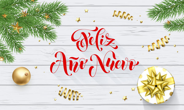 Feliz Ano Nuevo Spanish Happy New Year golden decoration and calligraphy font on white wooden background for greeting card. Vector Christmas gold shiny star on Xmas tree for winter holiday