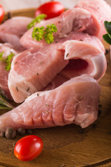 Few pork filets on chopping board with herbs and tomatoes