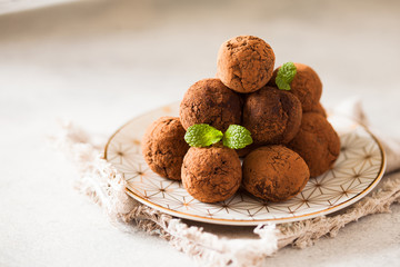 Сhocolate truffles with cocoa powder on white dessert plate