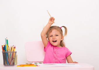 A little girl at the table and drawing with watercolors