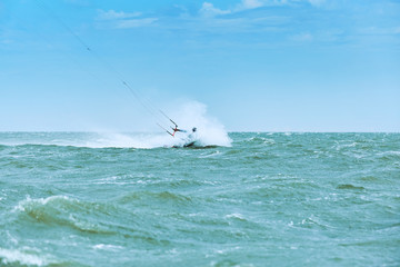 Man riding a kite surfing on the waves in the summer.