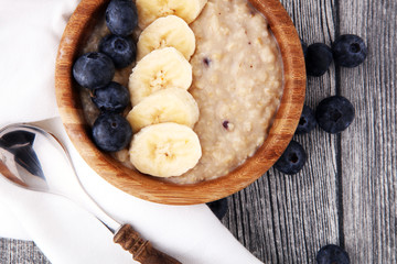 Bowl of oatmeal porridge with banana, blueberries on rustic table, hot and healthy food for Breakfast