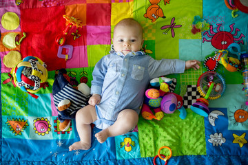 Obraz premium Happy three months old baby boy, playing at home on a colorful activity blanket