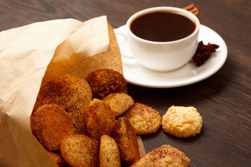 Coconut biscuit in a paper bag with coffee on a wooden table