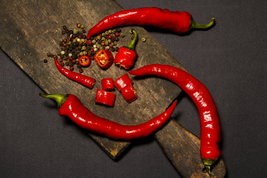 Red hot chili pepper corns and pods on dark   background, top view.