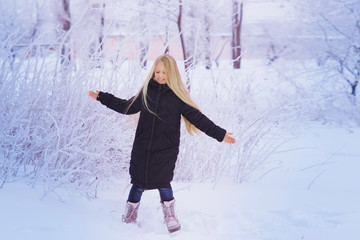 Winter girl blowing snow. Beauty Joyful Teenage Model Girl having fun in winter park. Beautiful girl laughing outdoors. Enjoying nature.