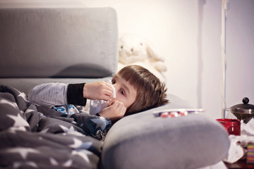 Sick child boy lying on the sofa with a fever
