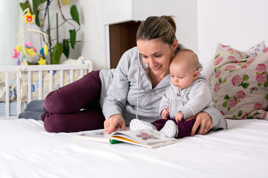 Young mother, reading a book to her baby boy, showing him pictures