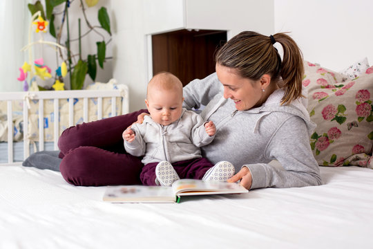 Young mother, reading a book to her baby boy, showing him pictures