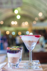 Blueberry and strawberry cheese tart contain in two style of glasses, display on wooden block for sale with blur background, food and dessert business marketing and advertising concept.