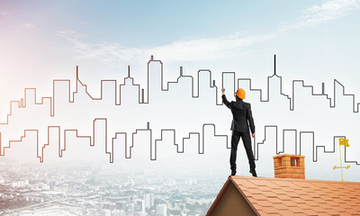 Man architect draw silhouette of modern city on blue sky. Mixed media
