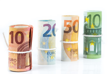 Several rolls of euro banknotes stacked by value from ten, twenty, fifty and one hundred euros isolated on white background.