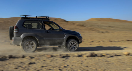 A jeep drives through the desert