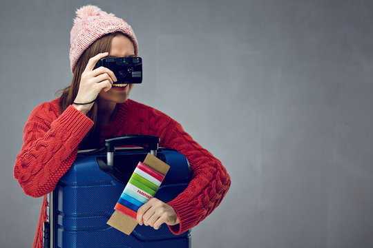 Woman dressed red sweater taking pictures with camera.
