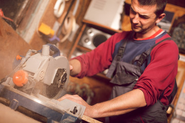 Carpenter using circular saw for cutting wooden boards
