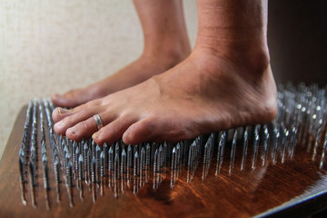 A girl stands on a board with nails