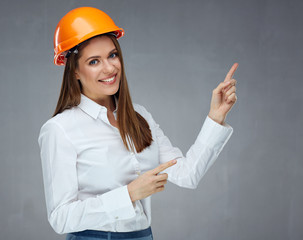 Smiling businesswoman wearing builder helmet pointing finger up.
