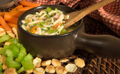 Homemade Chicken Noodle Soup. Fresh hot bowl of chicken noodle soup surrounded by crackers, celery, and carrots.