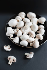 Mushroom champignon on black  background, sliced and whole.  Autumn raw  Mushrooms.
