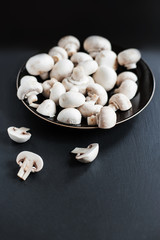 Mushroom champignon on dark   background, sliced and whole with copy space. Cooking delicious organic mushroom. Gourmet food