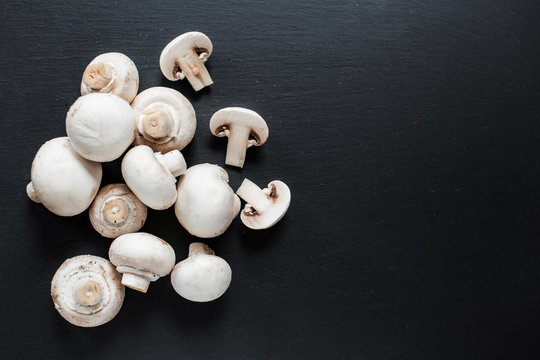 Fresh Mushroom champignon on dark   background, sliced and whole with copy space, ready for cooking