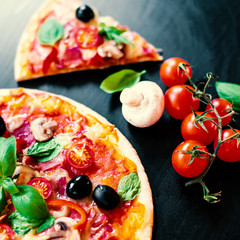 Italian Pizza slices with  melting cheese and olives served at a pizzeria or restaurant on black board with copy space