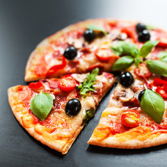 Mozarella Pizza slices with  melting cheese and olives served at a pizzeria or restaurant on black board with copy space