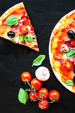 Italian Pizza slices with  melting cheese and olives served at a pizzeria or restaurant on black board with copy space