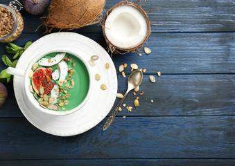 Cup of green spirulina smoothie with fruits on table. Healthy vegan food concept