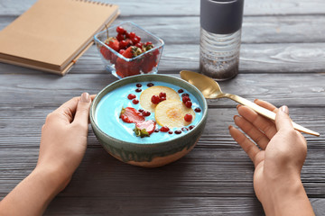 Woman eating blue spirulina smoothie at table. Healthy vegan food concept