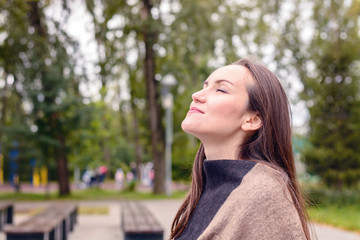 Portrait of young beautiful woman doing breath of fresh autumn air in a green Park. the concept of pure atmospheric air, the environment