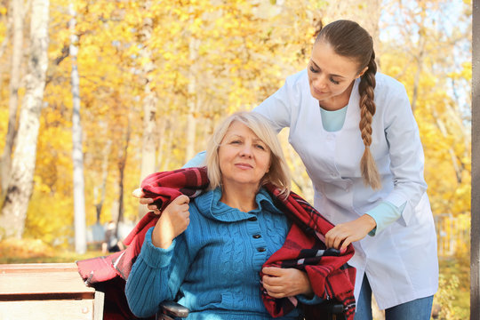 Disabled senior woman and young nurse in park