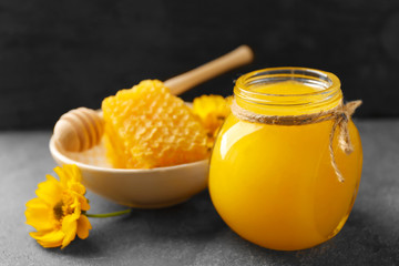 Aromatic honey in jar and dish with honeycomb on table