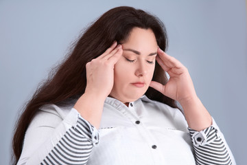 Overweight young woman on light background