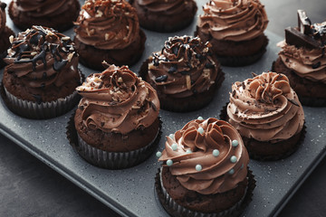 Muffin tin with tasty chocolate cupcakes on grey background